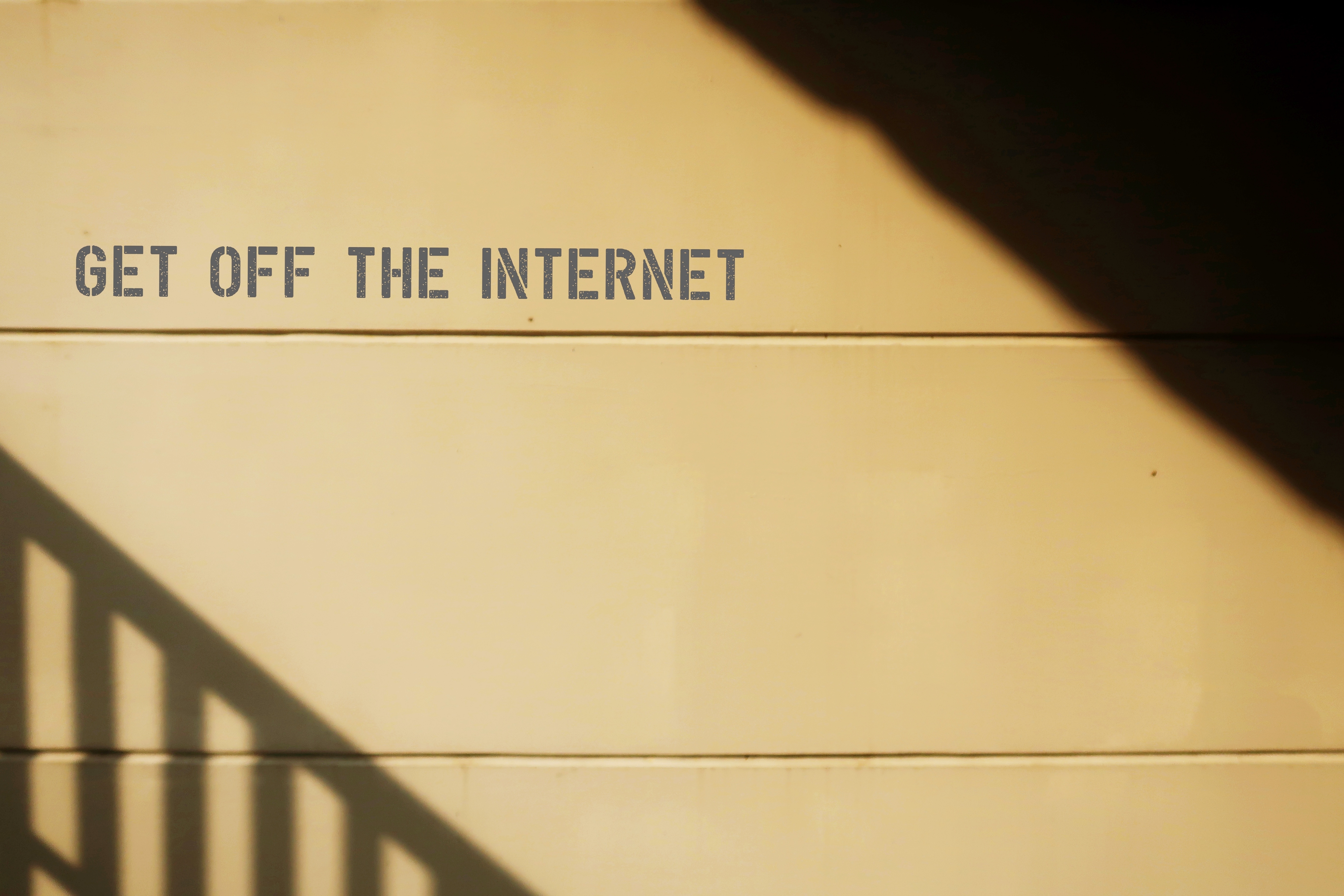 Wall with shadowed staircase railing and text.