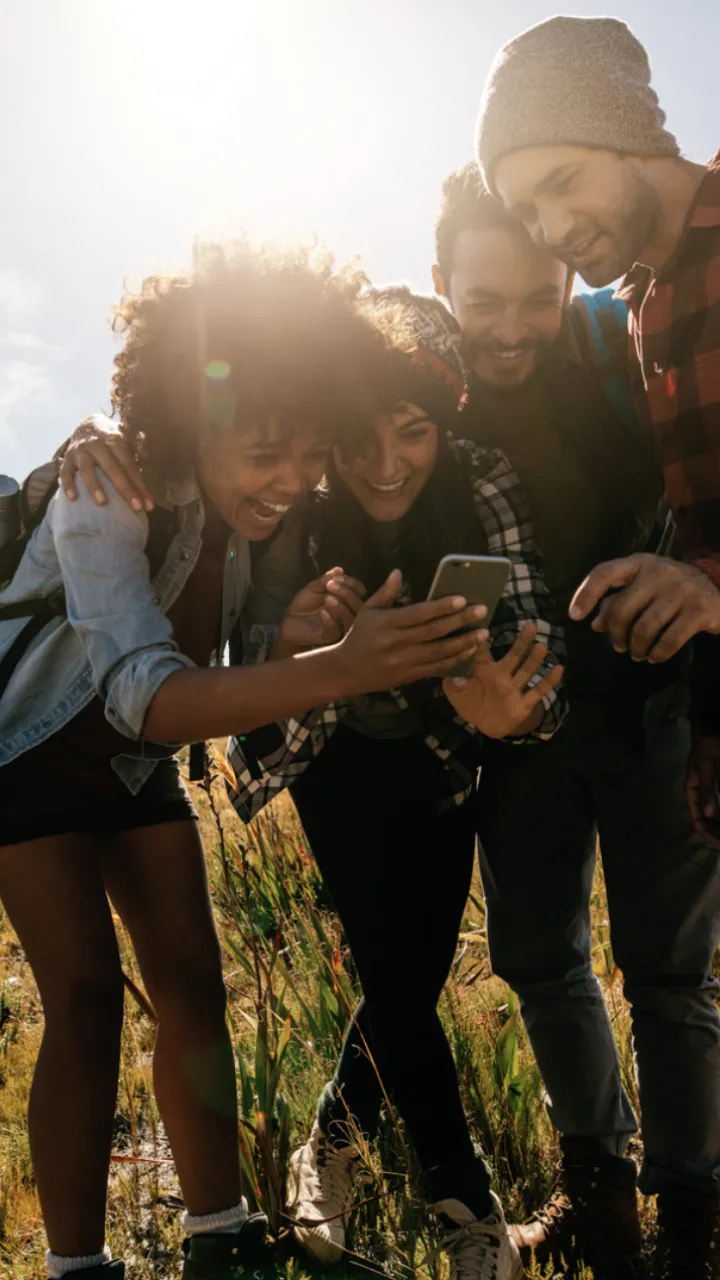 A group of people outside laughing at a phone