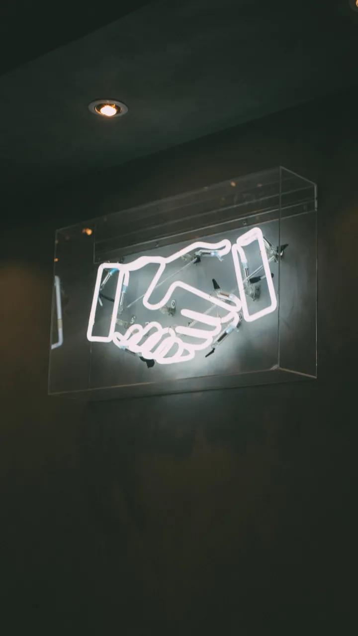 A neon light of two hands shaking