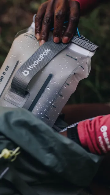 Hand pulling water reservoir out of backpack close up