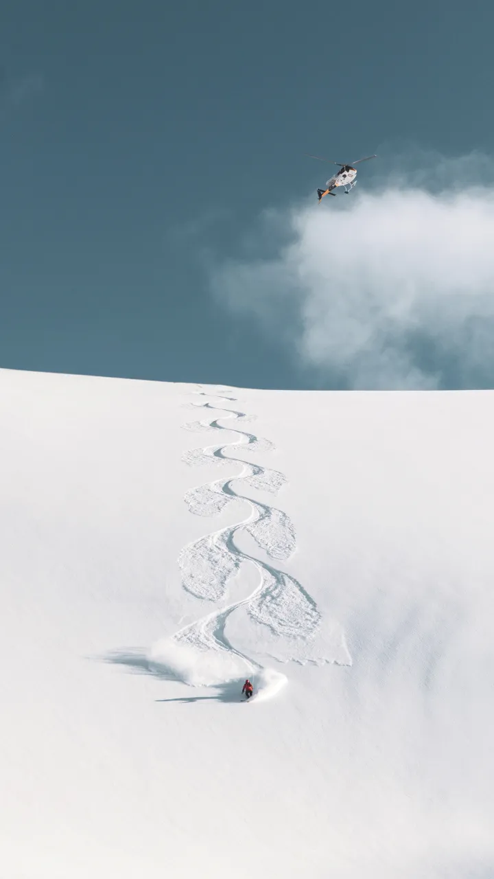A person skiing with a helicopter in the background
