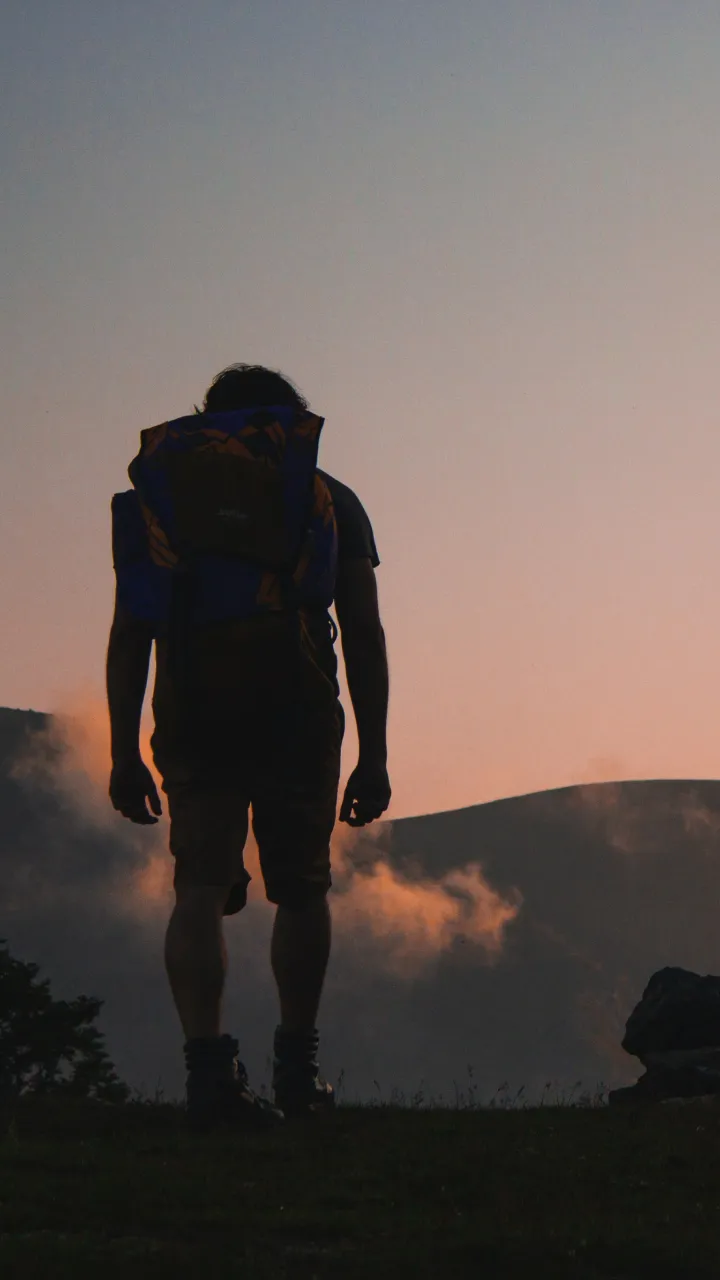 A silhouette of someone hiking with mountains in the background