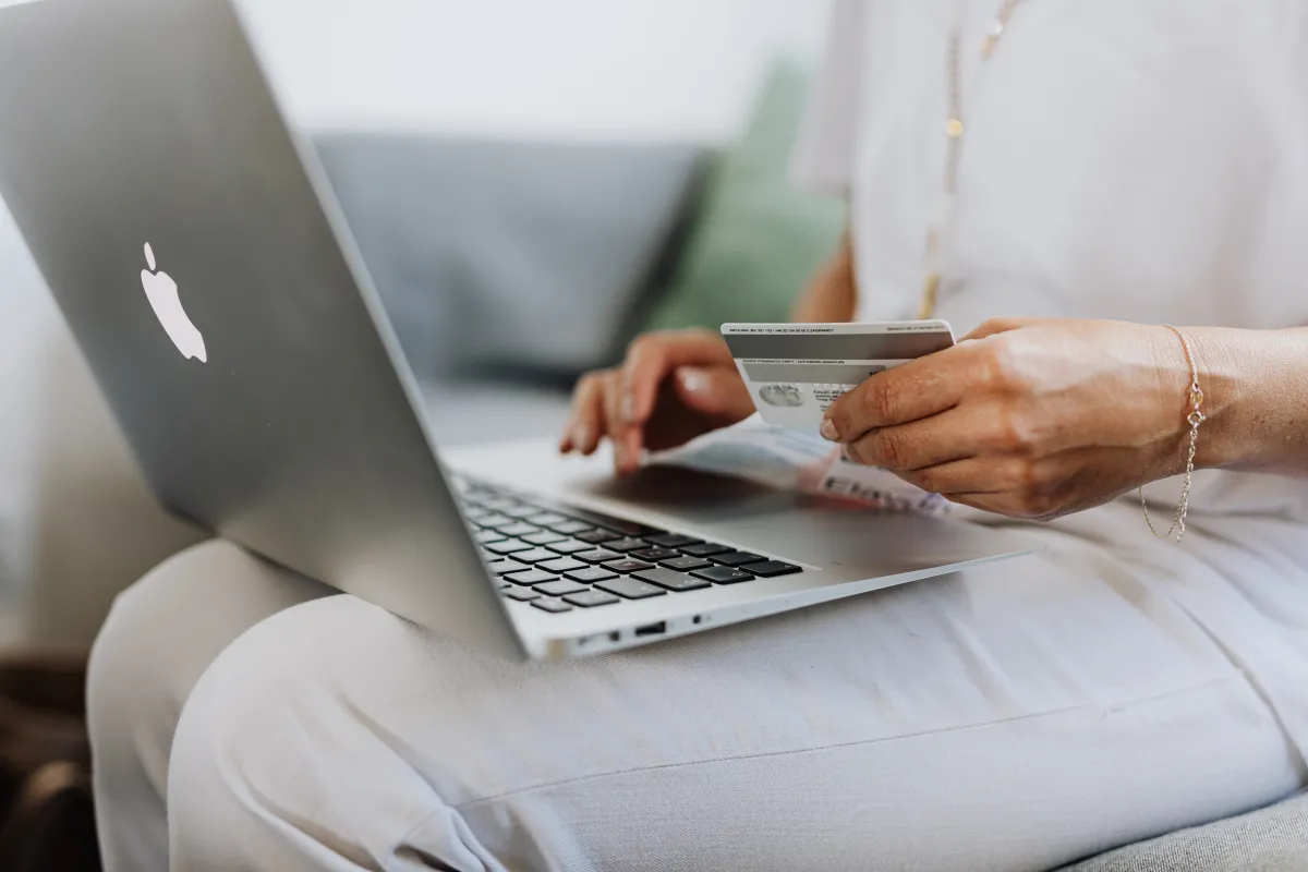 Person holds credit card with computer on their lap