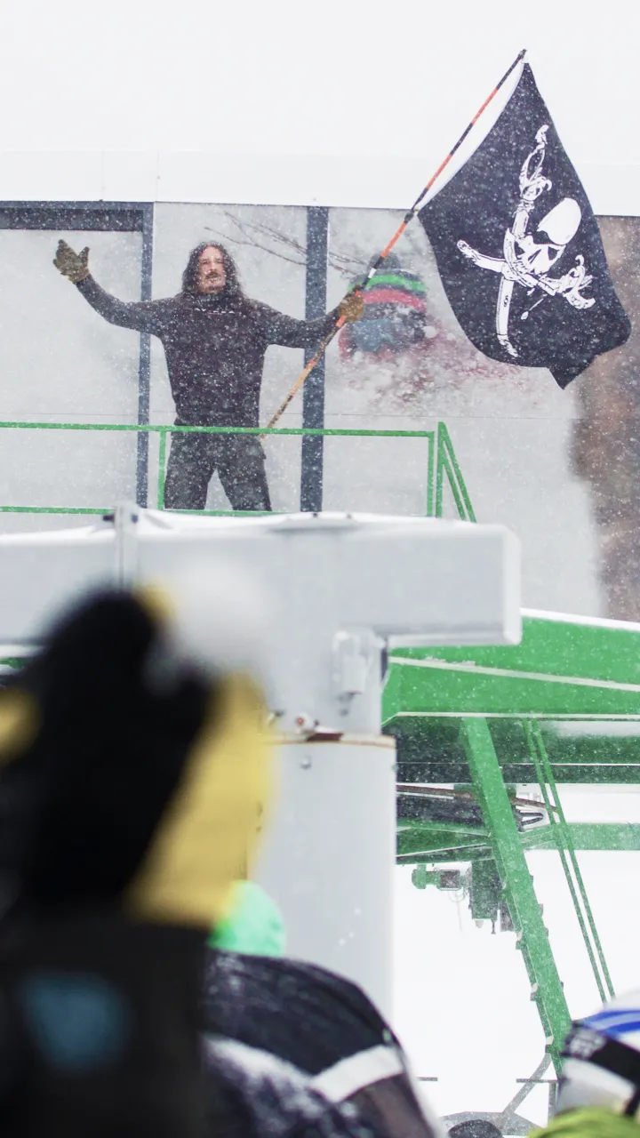 Man standing at base of chair lift waving a pirate flag