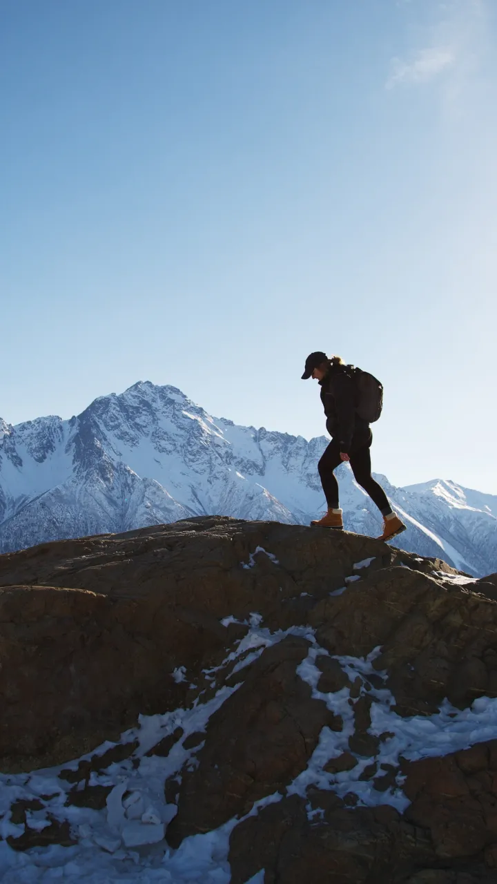 A hiker walking along a ridge with mountains in the background