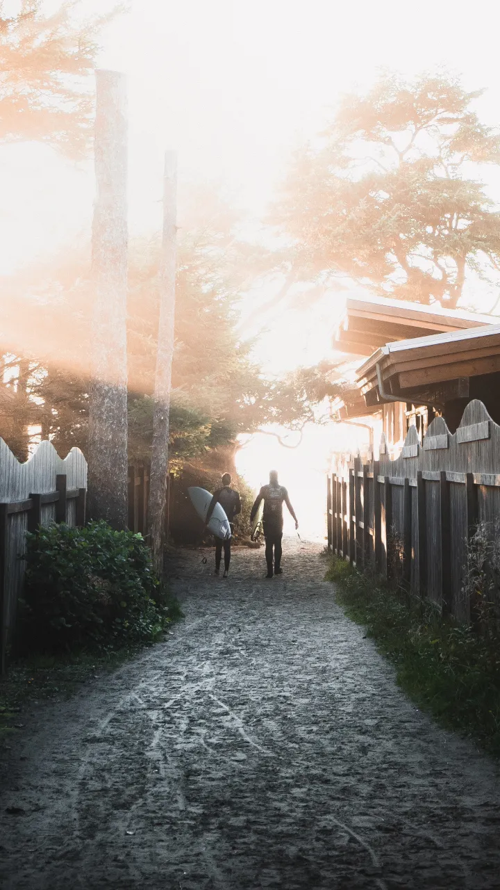 Two surfers walking down a path