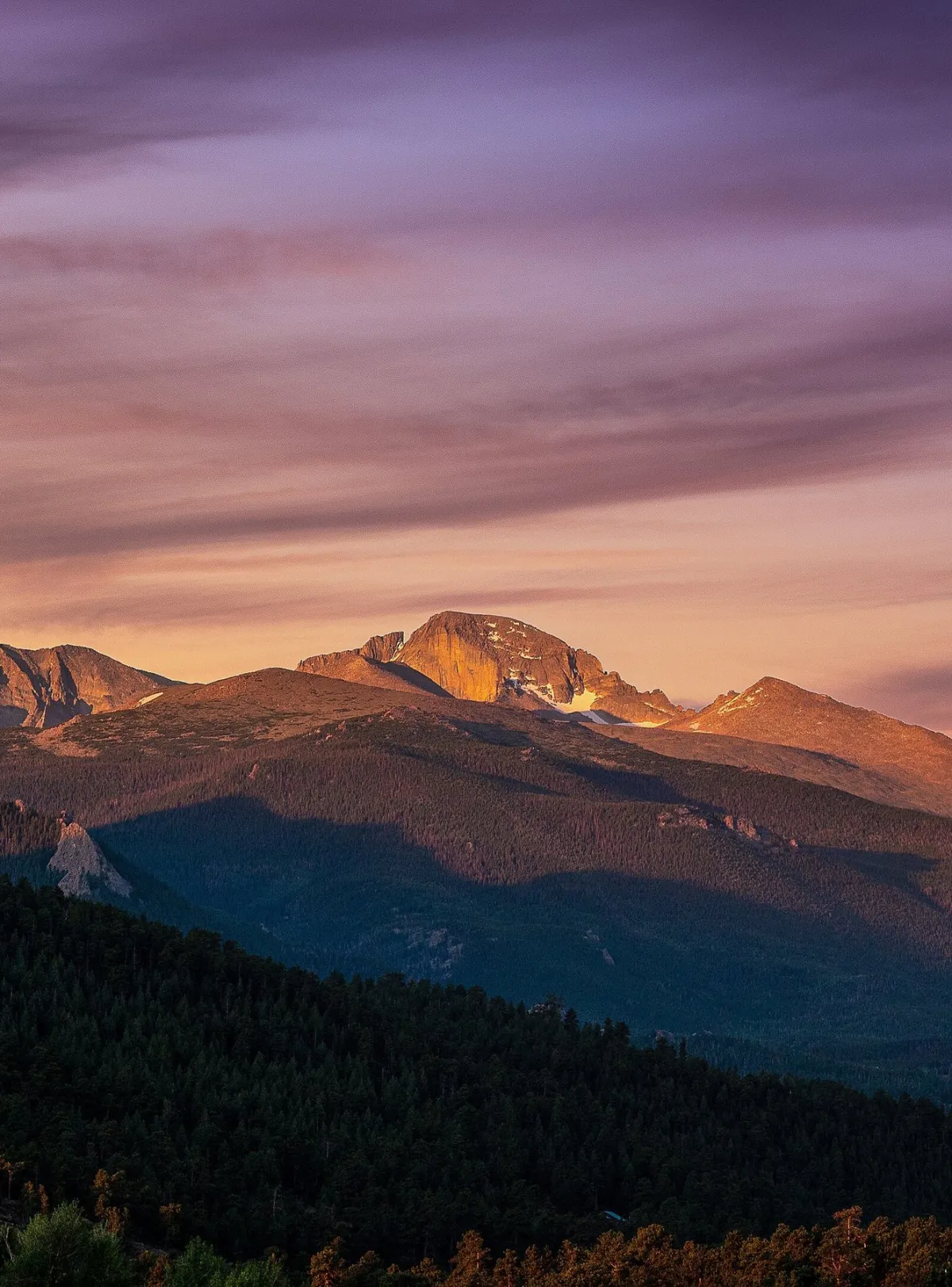 Mountains at sunset with purple and orange sky.