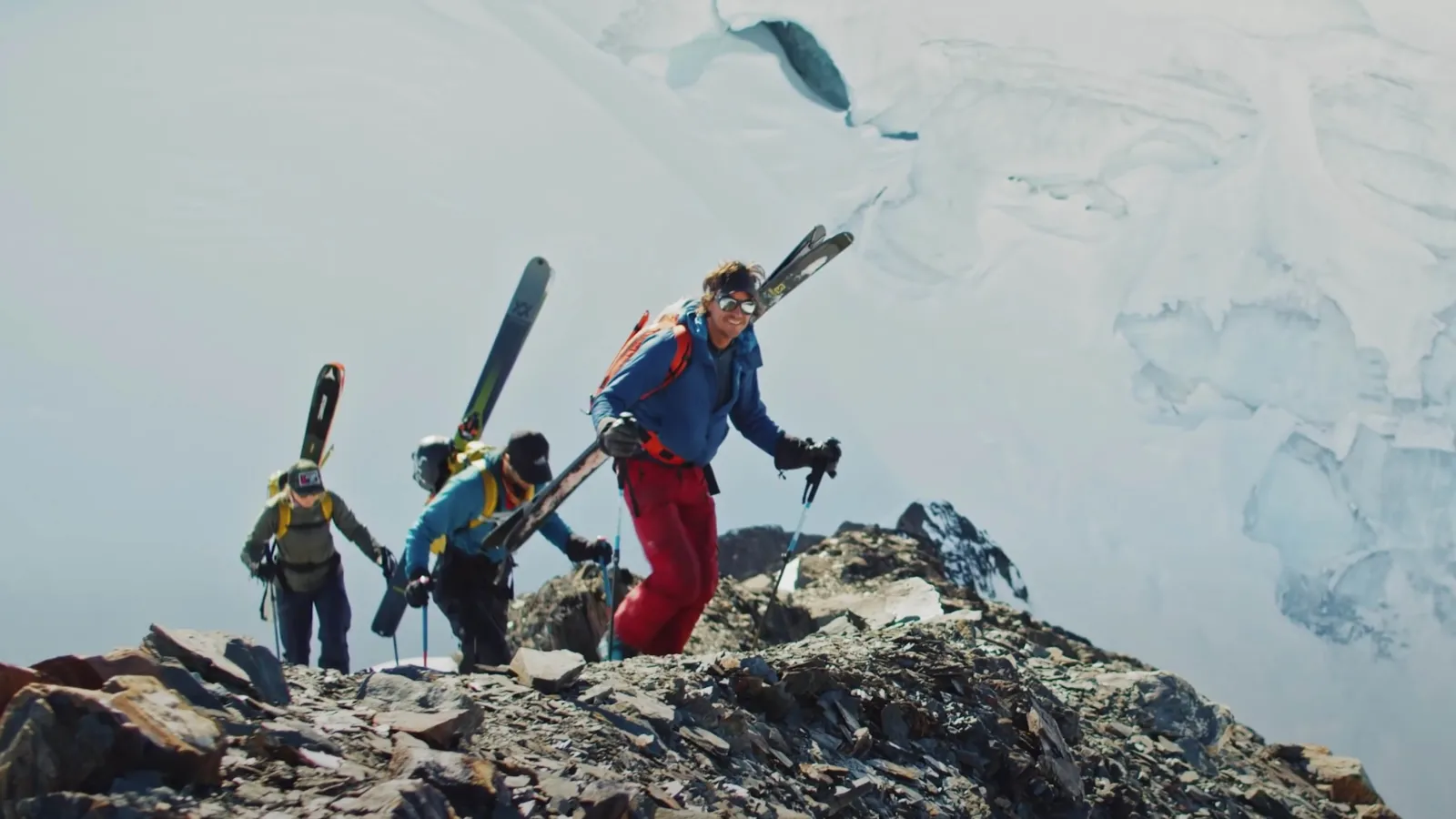 3 people climbing with skis on their backs