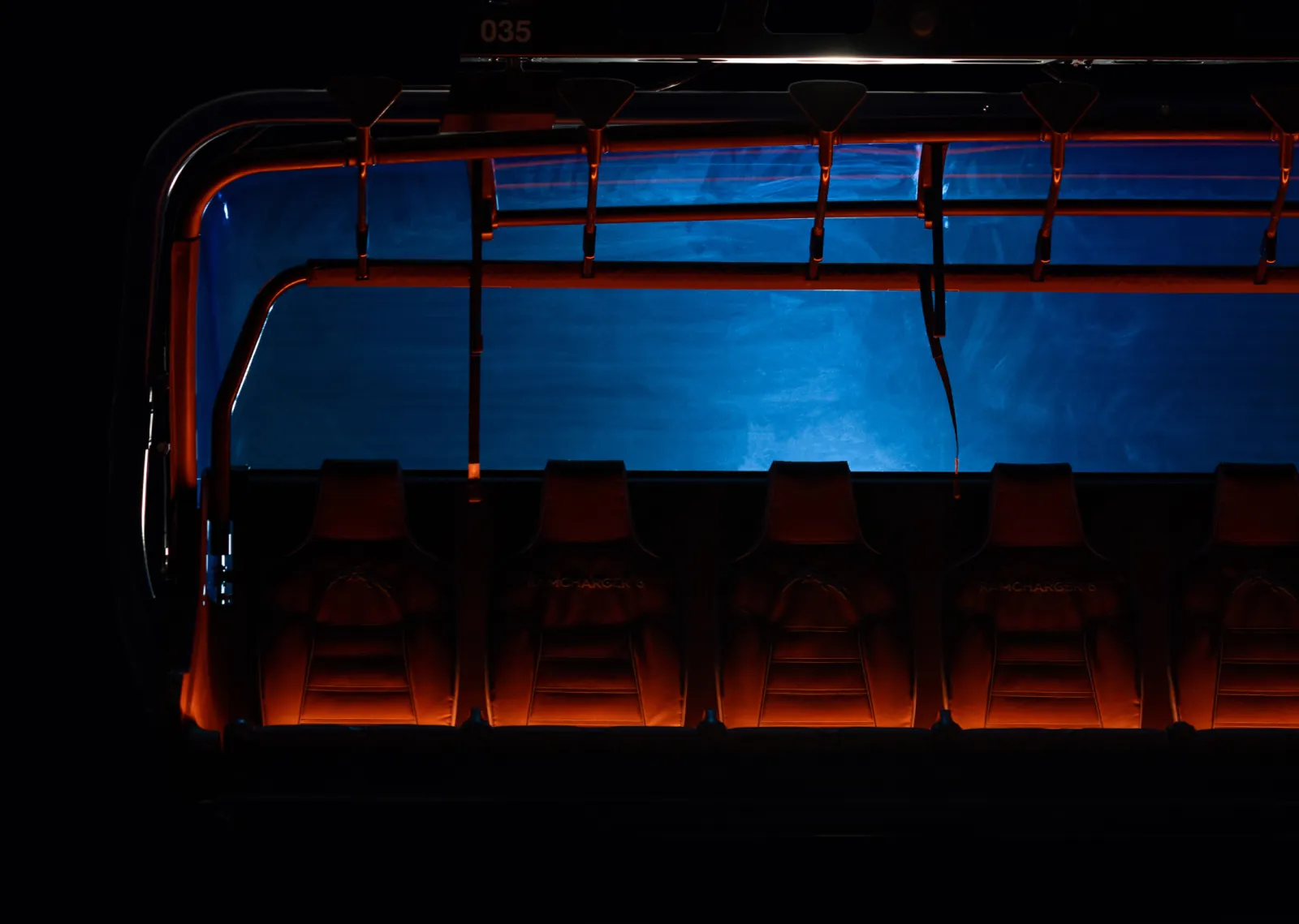 Dark room with five leather seats, blue and orange lighting.