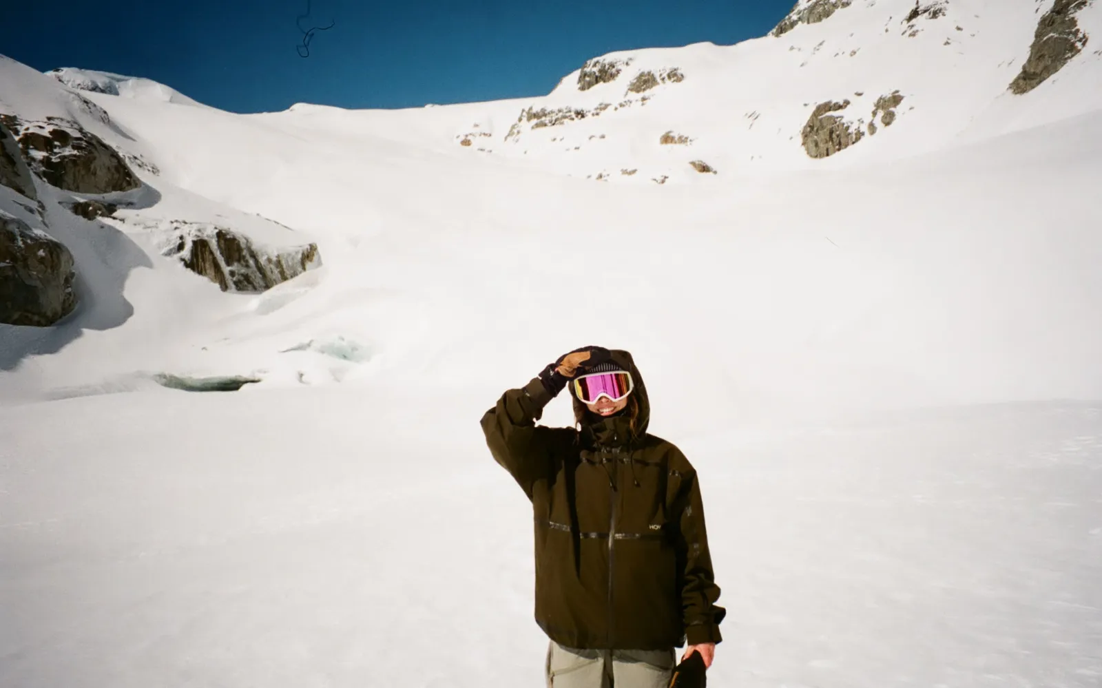 Person in ski gear on snowy mountain, clear blue sky.