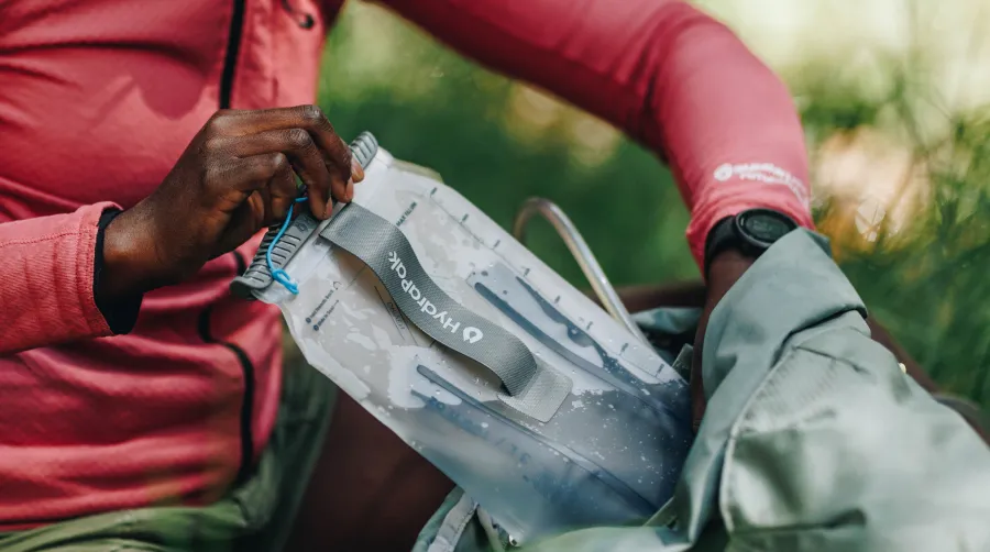 Hand pulling water reservoir out of backpack close up