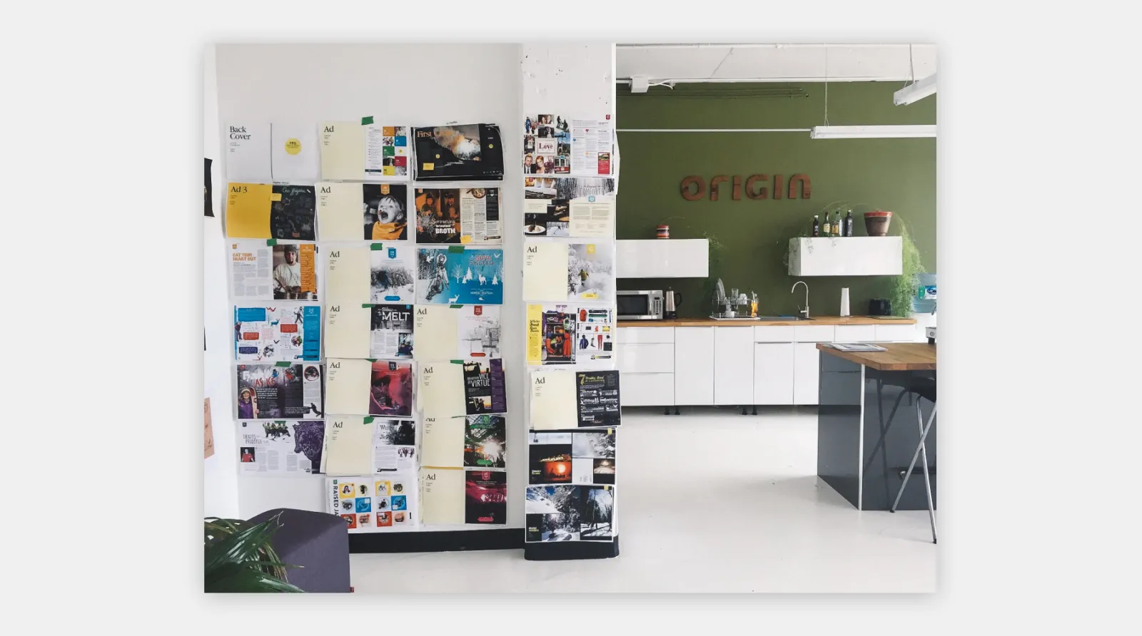 An office with magazine pages laid out on a wall