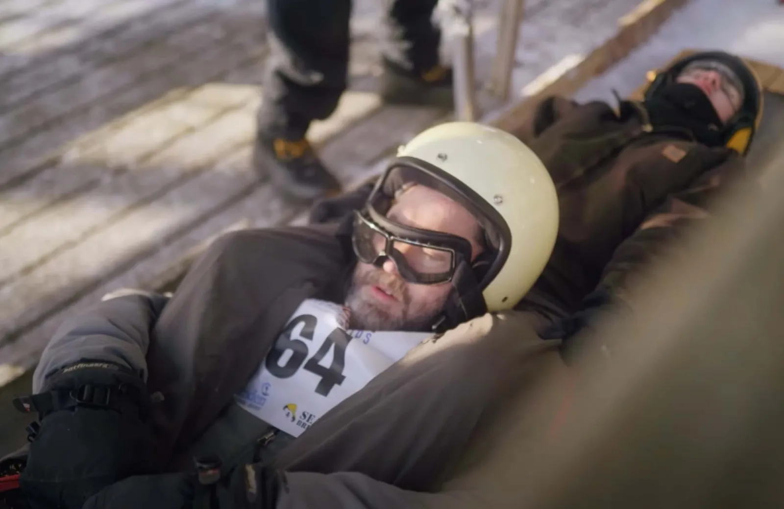 2 people laying down about to go down the sled track