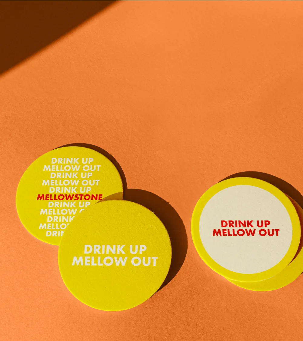 Bright yellow and white drink coasters on an orange surface.
