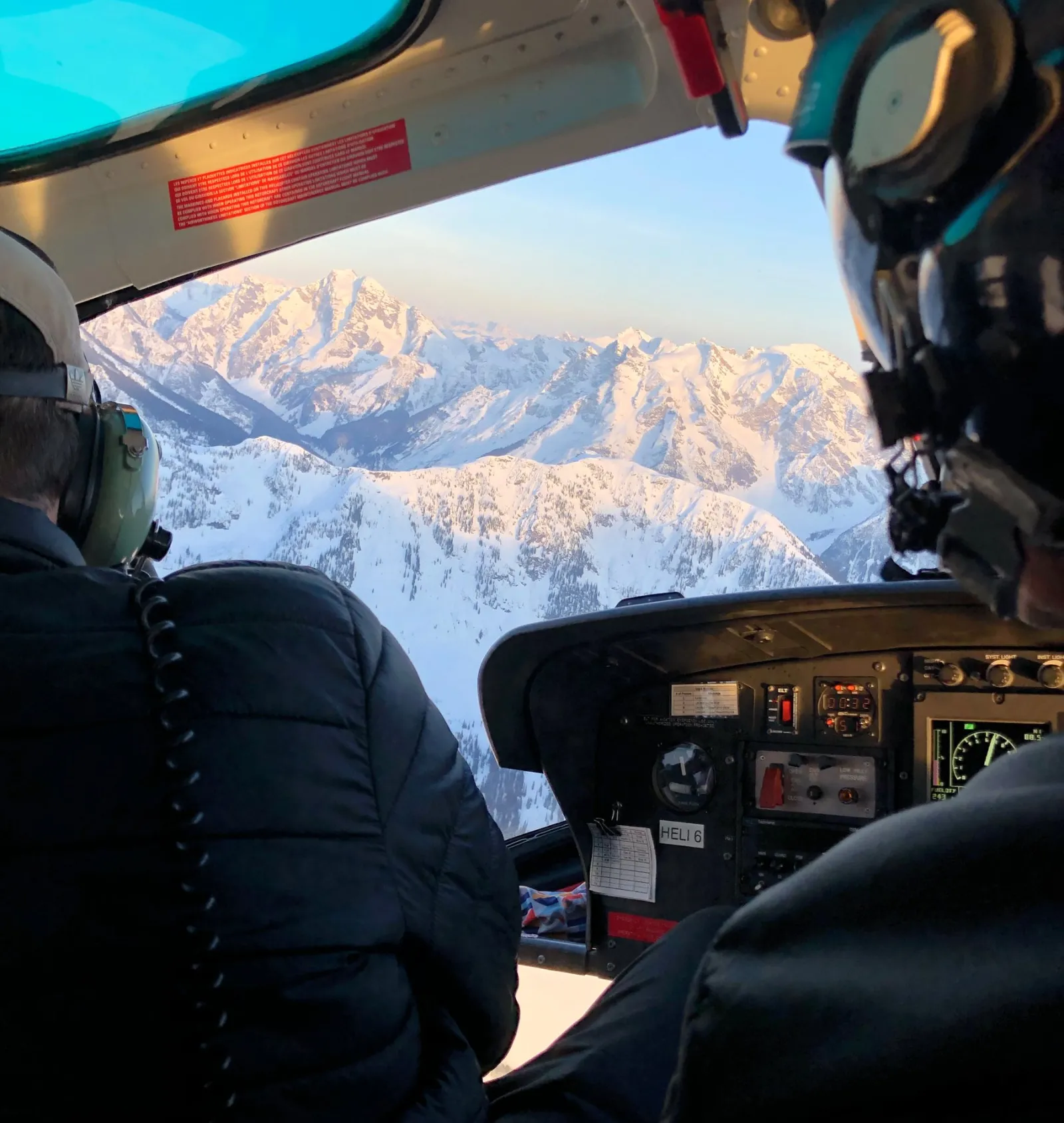 View from inside a helicoptor over a snowy mountain range