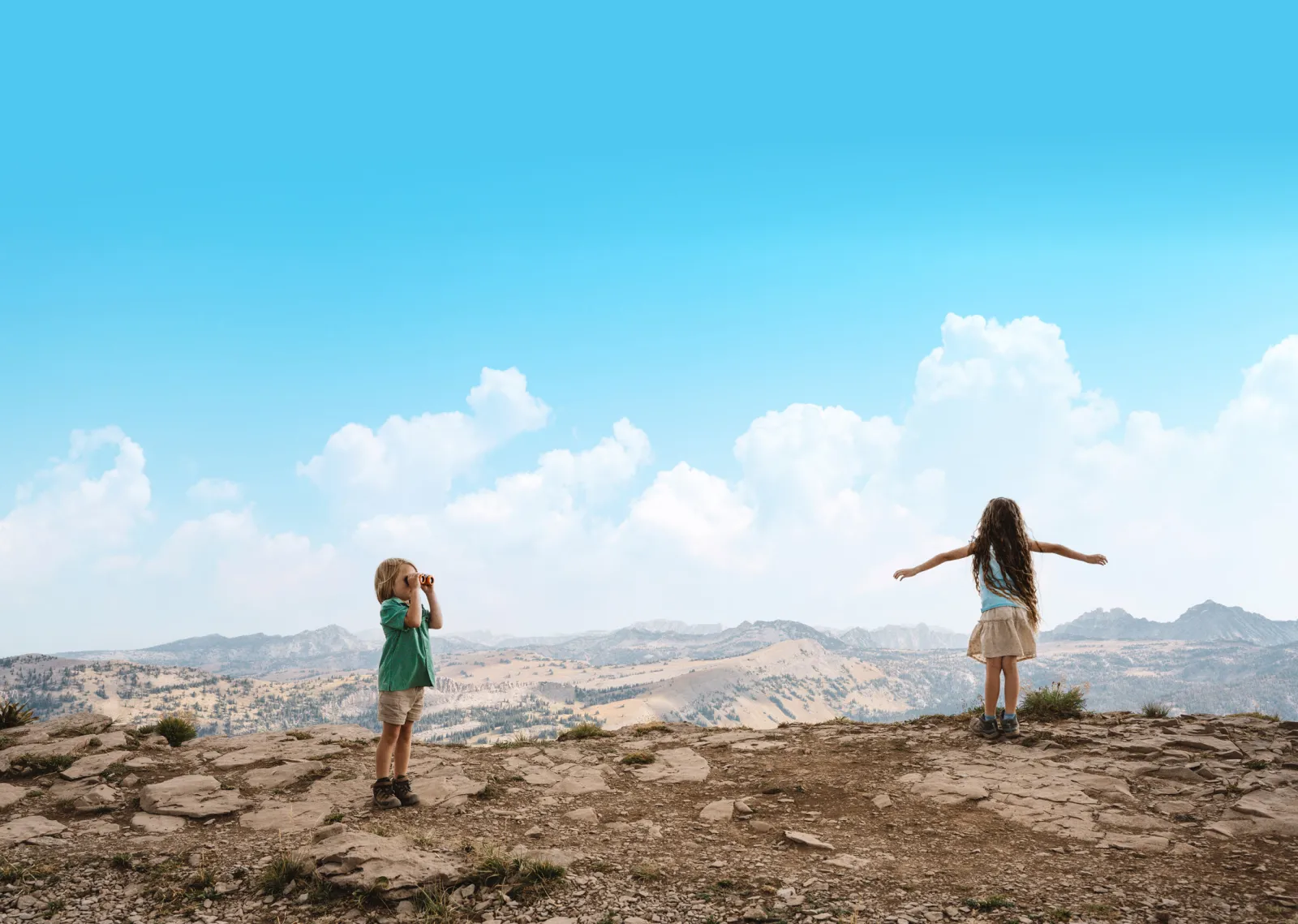 Children exploring a rocky landscape under a clear blue sky.