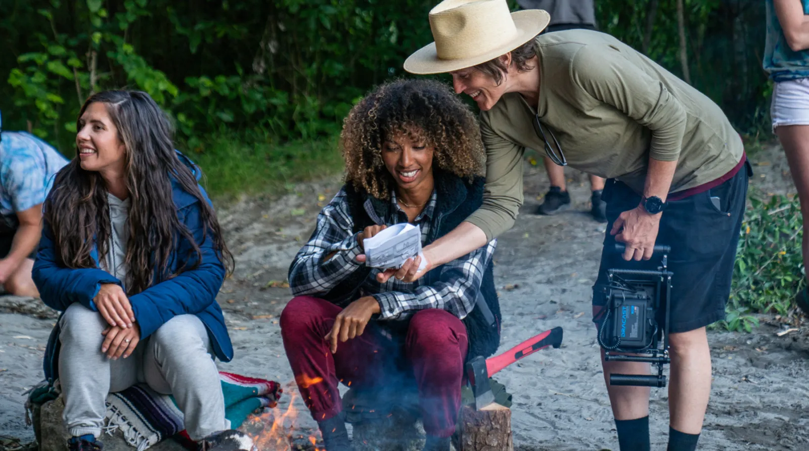 Director speaking to talent on set around a campfire