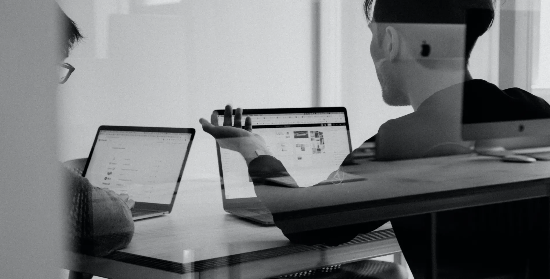 Black and white photo of two people sitting at their laptops