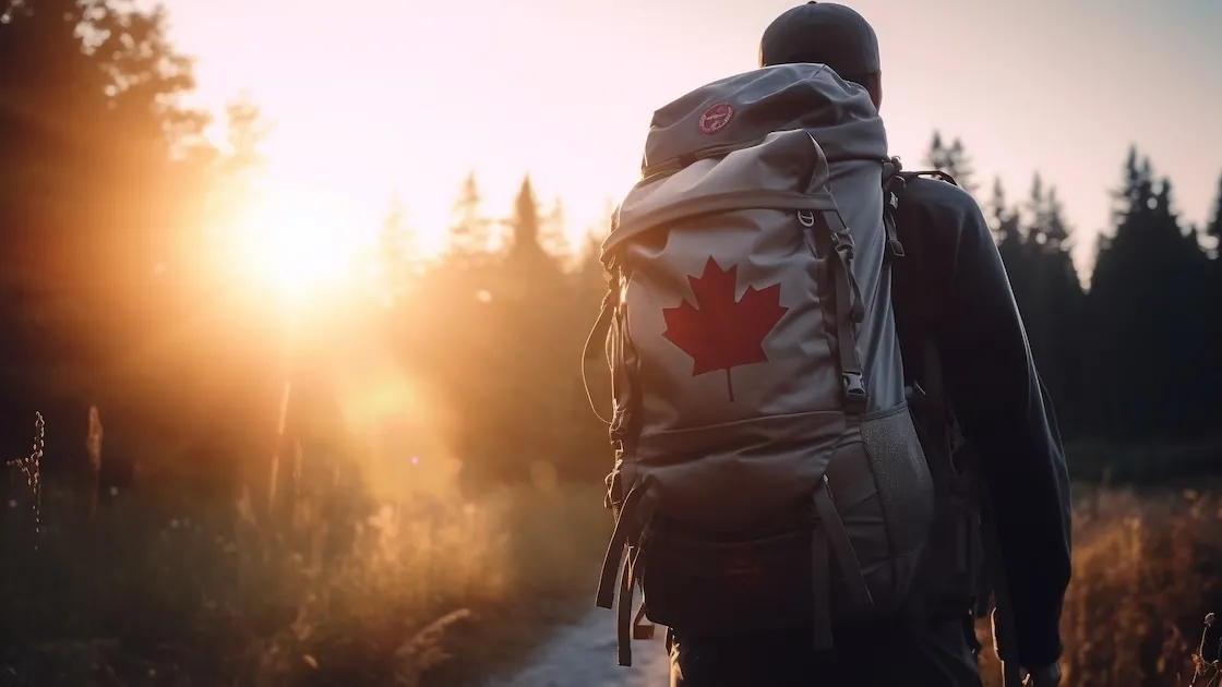 Backpacker with Canadian flag at sunset on forest path.