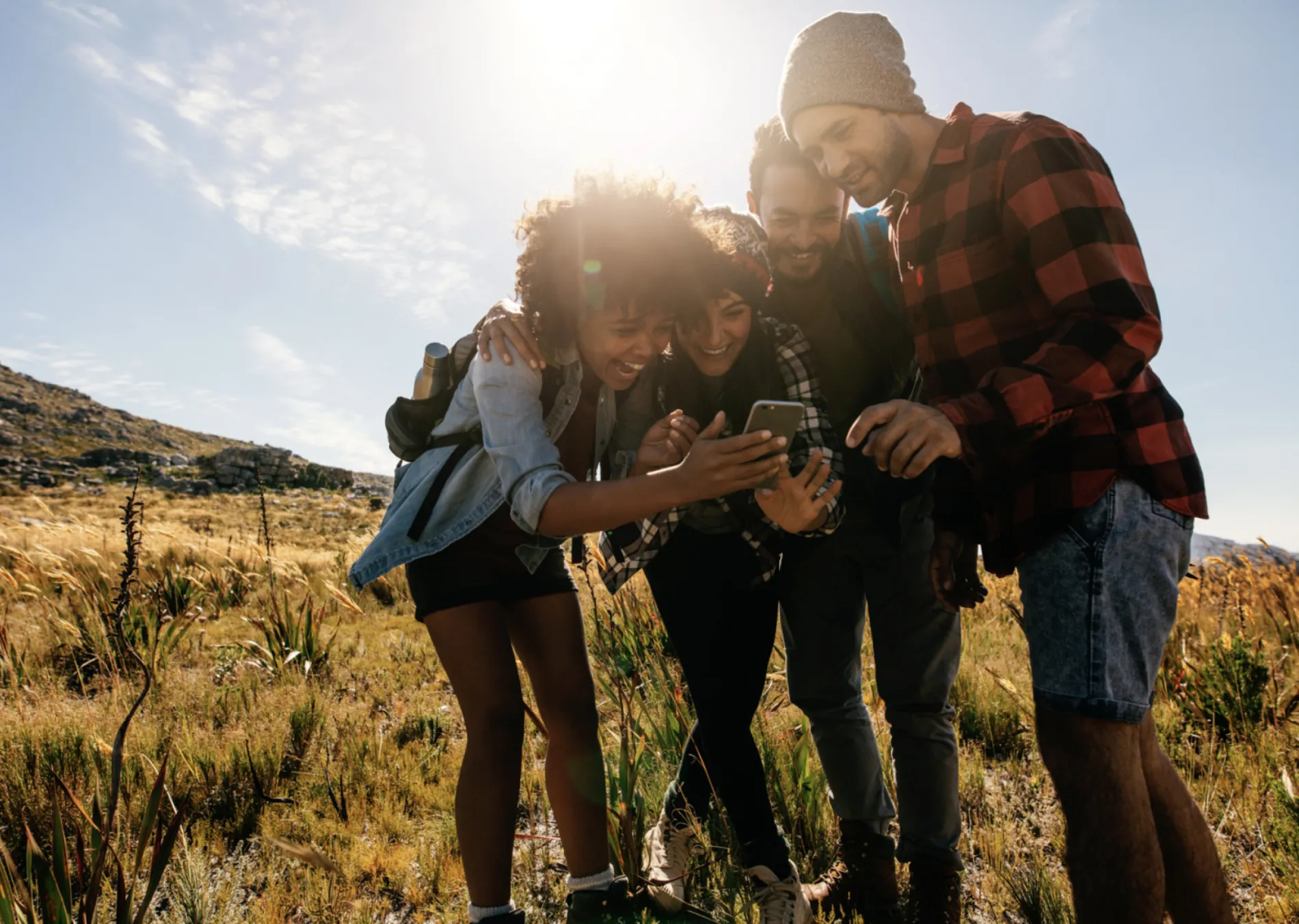 A group of people outside laughing at a phone