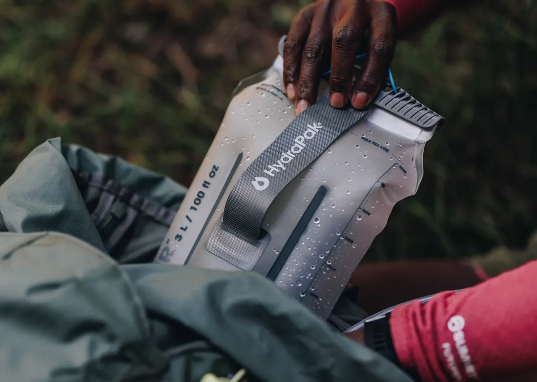 Hand pulling water reservoir out of backpack close up