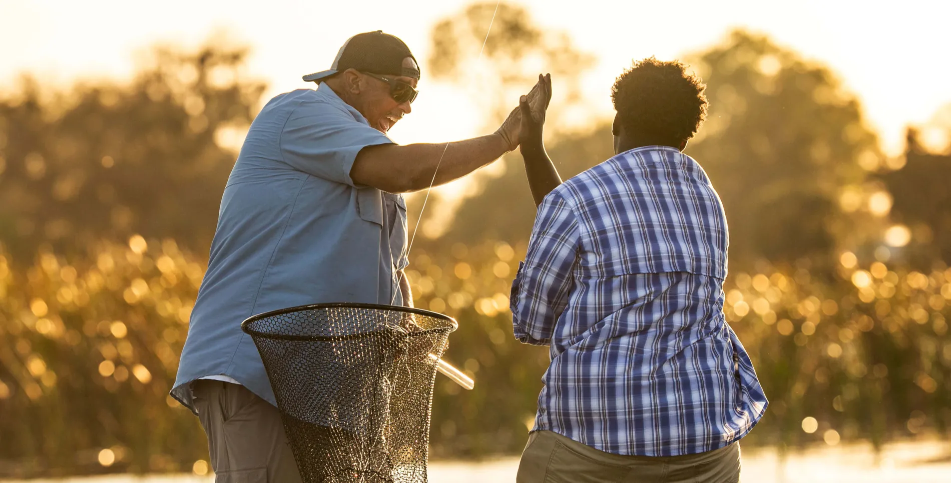 Friends high-fiving, fishing on the river