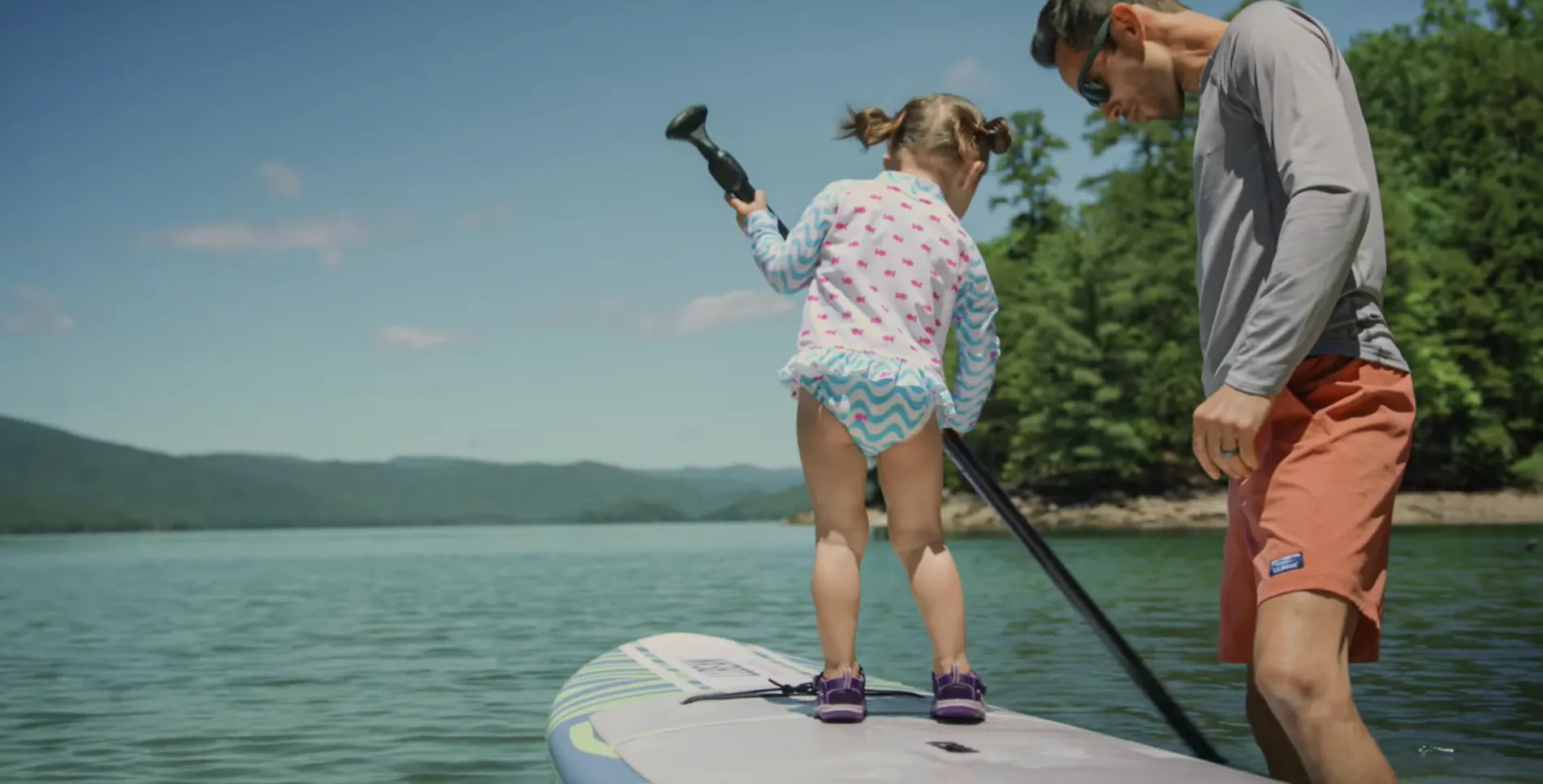 Father and daughter standing on paddle board