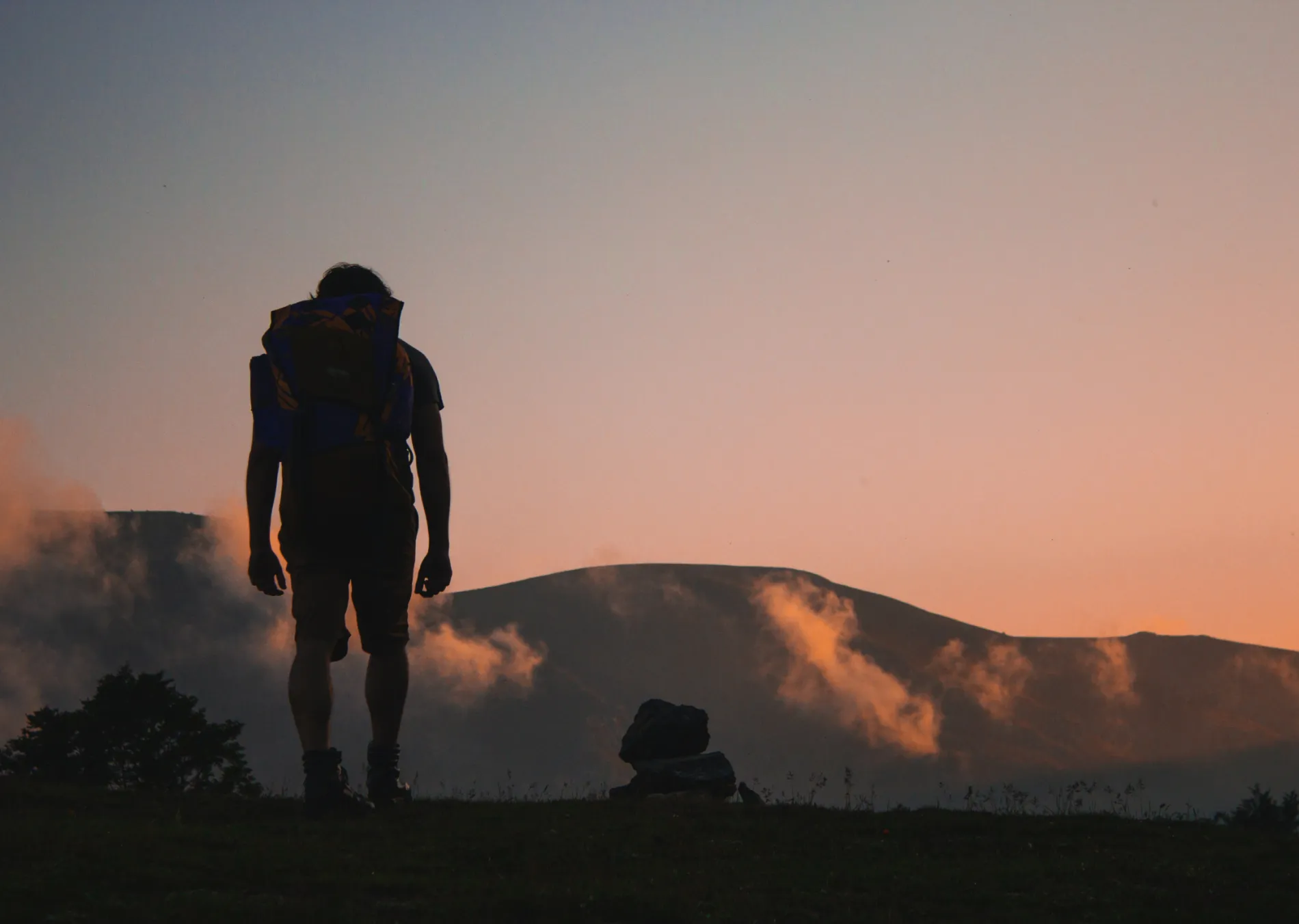 A silhouette of someone hiking with mountains in the background