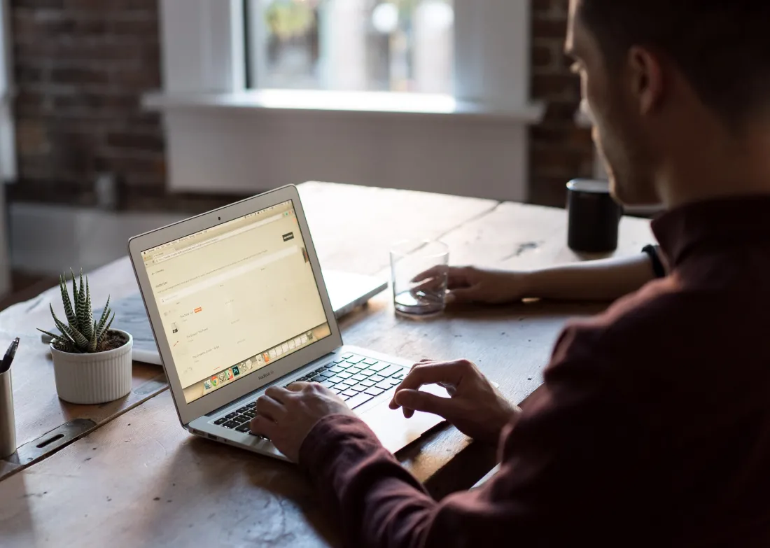 man typing on computer at a table