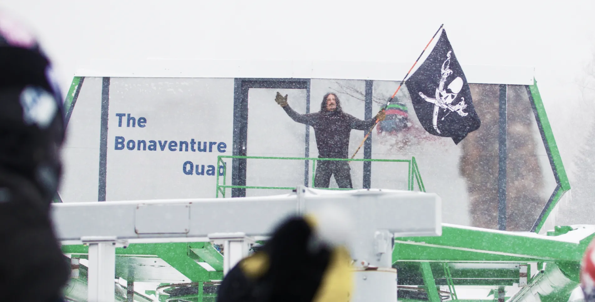 Man standing at base of chair lift waving a pirate flag