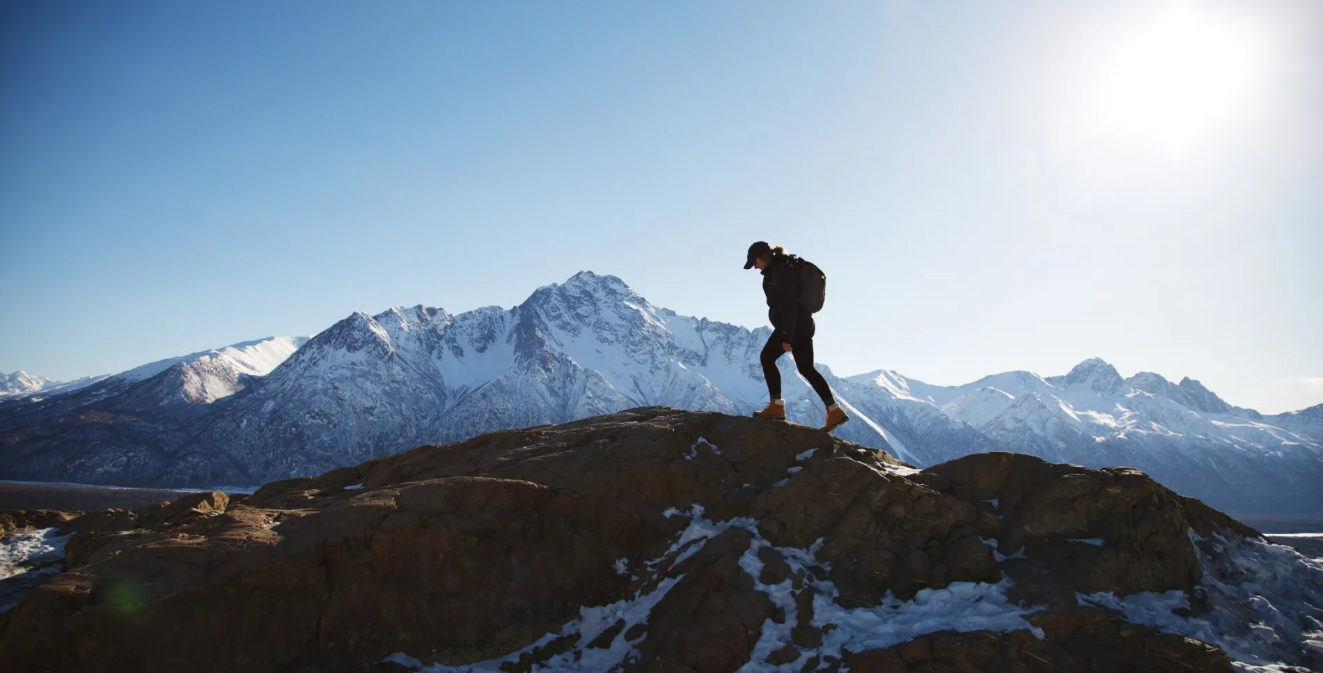 A hiker walking along a ridge with mountains in the background