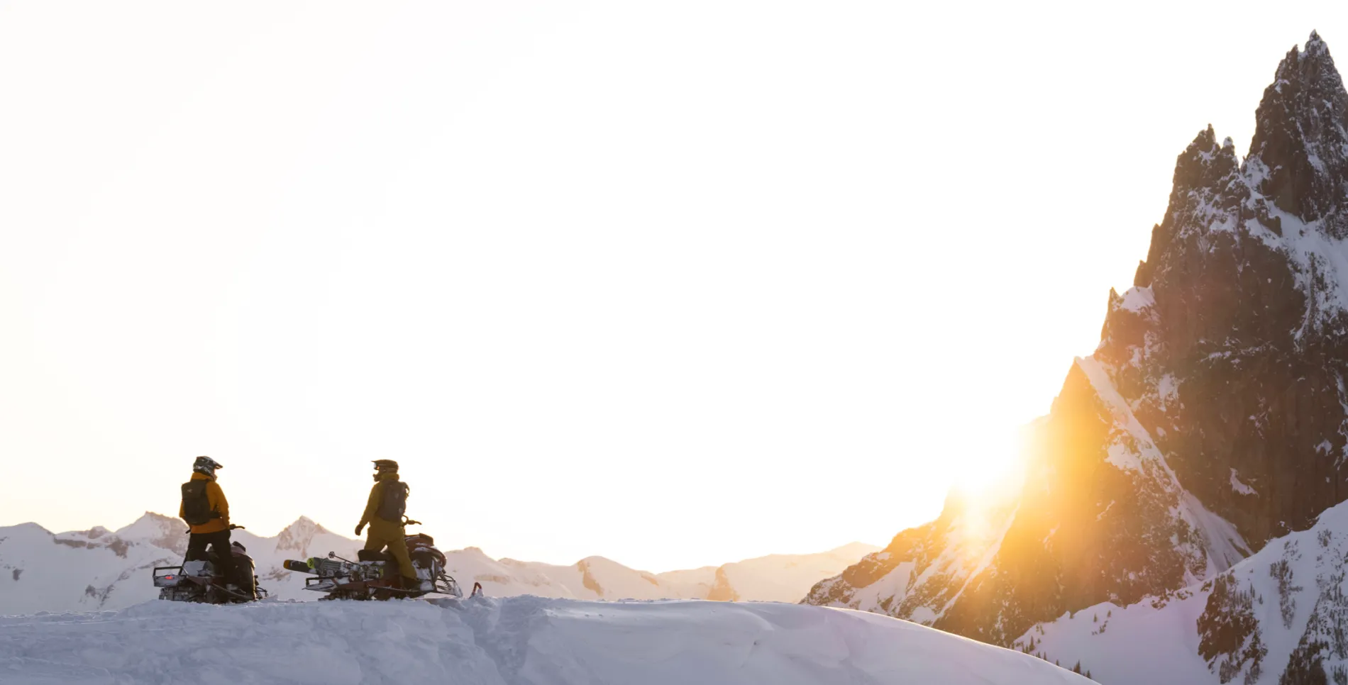 two people sitting on their sleds looking at the sun set