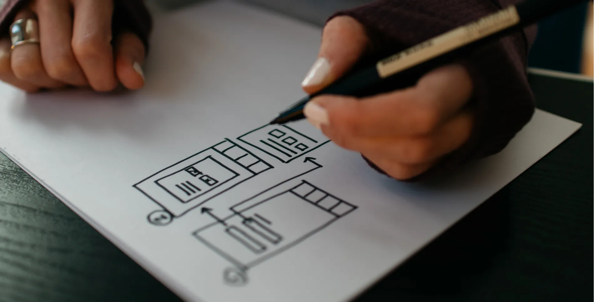 Hands drawing a mobile UX layout