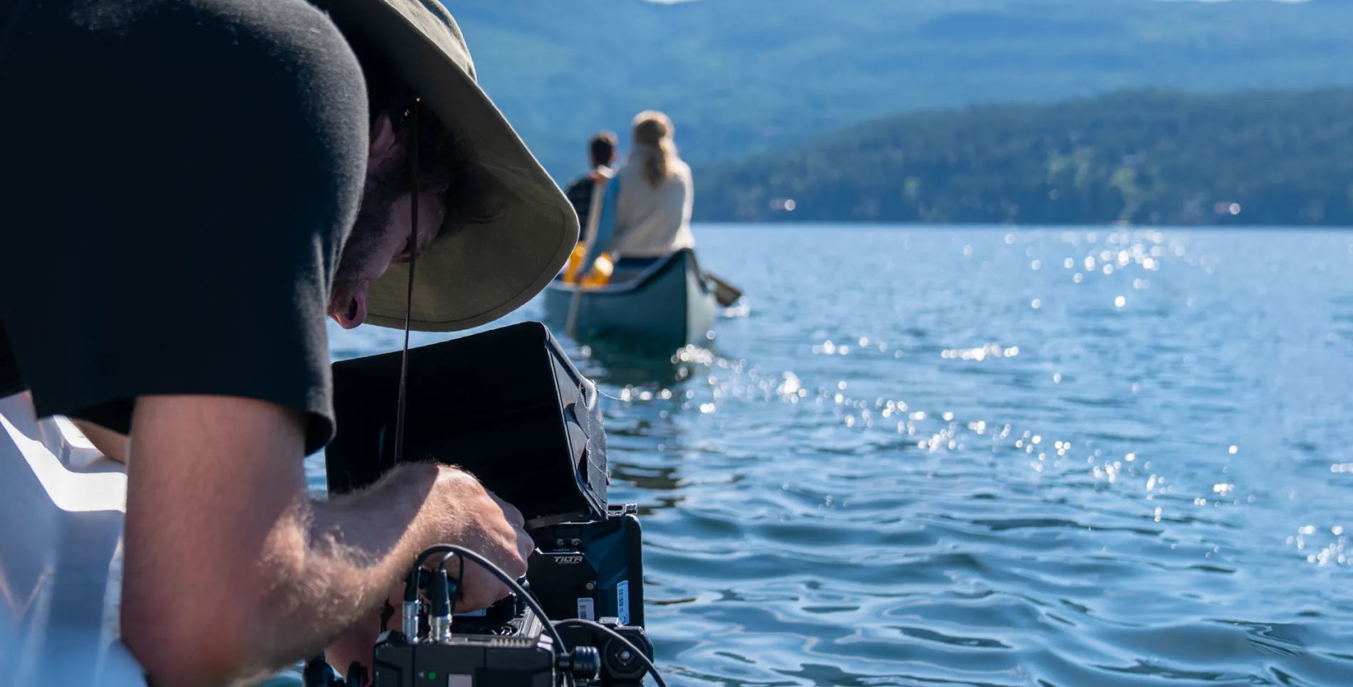 Someone filming 2 people in a canoe on a lake