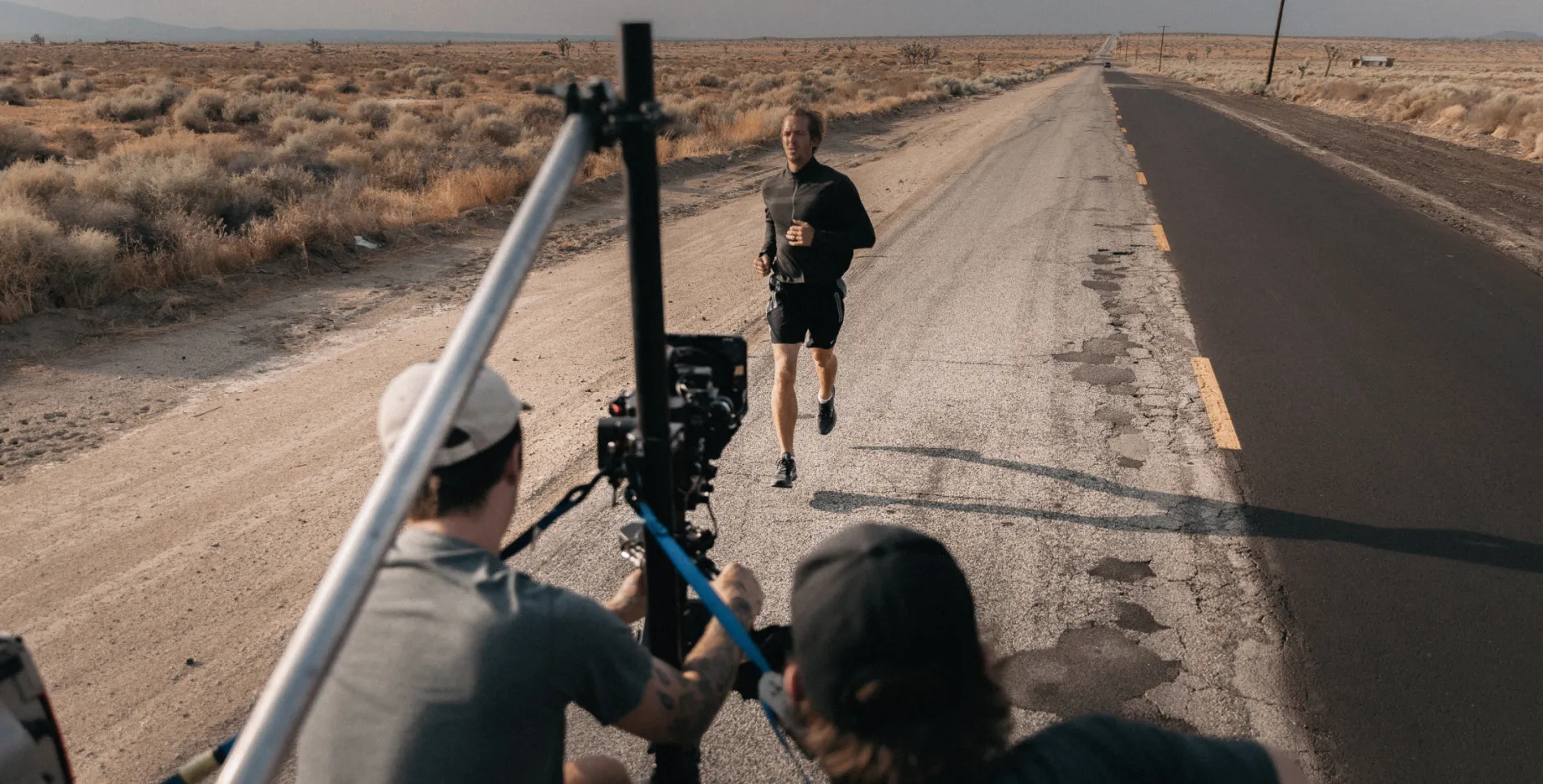 A person running along a road while being filmed by a video crew